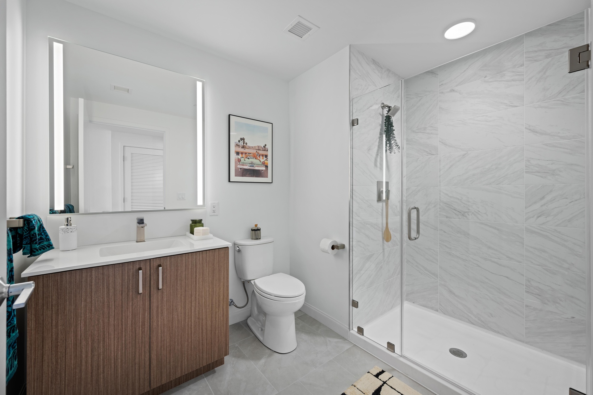 Studio bathroom with a lit mirror and shower.